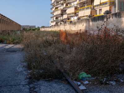 Questa parete da una parte affianca una stradina ricoperta da erba incolta...